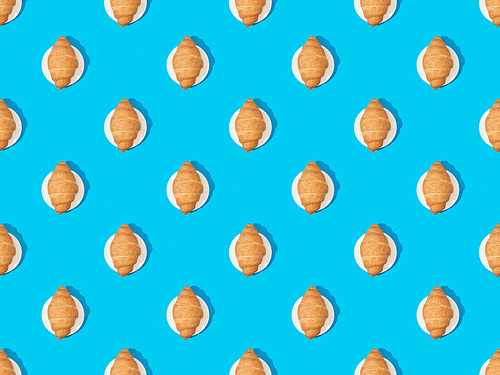 top view of fresh croissants on plates on blue, seamless background pattern