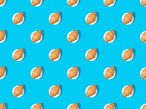 top view of fresh croissants on plates on blue, seamless background pattern