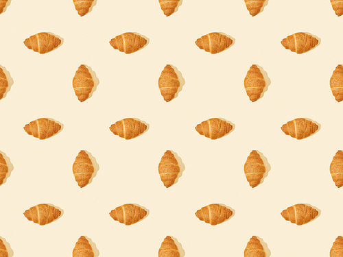 top view of delicious fresh croissants on beige, seamless background pattern
