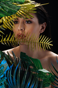 Portrait of beautiful girl with green leaves isolated on black