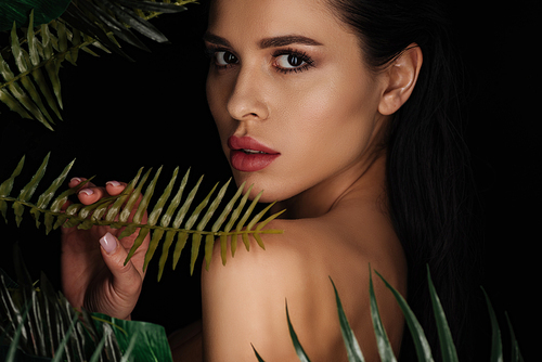 Beautiful woman touching fern leaf and  isolated on black