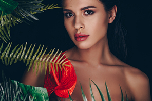 Beautiful girl with red anthurium and leaves  isolated on black