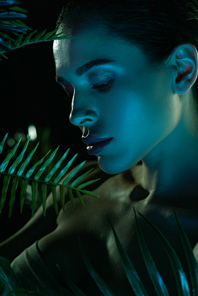 Beautiful woman with green leaves isolated on black