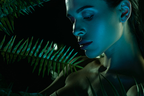 Girl near fern leaves on black background