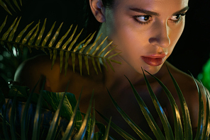 Selective focus of beautiful woman and green leaves isolated on black