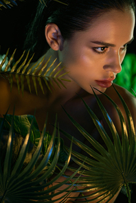 Brunette woman with green leaves isolated on black