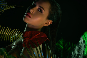 Selective focus of sexy woman with anthurium and leaves  isolated on black