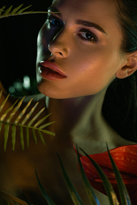 Portrait of woman  behind leaves and flower isolated on black