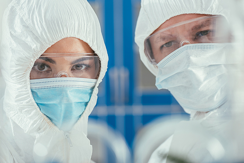 selective focus of biochemists in hazmat suites, medical masks and goggles 