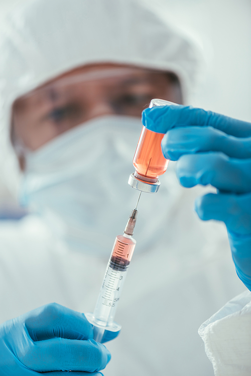 selective focus of biochemist taking medicine with syringe in laboratory
