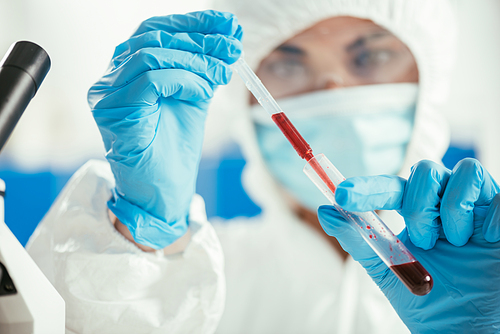 selective focus of biochemist taking blood sample from test tube with pipette