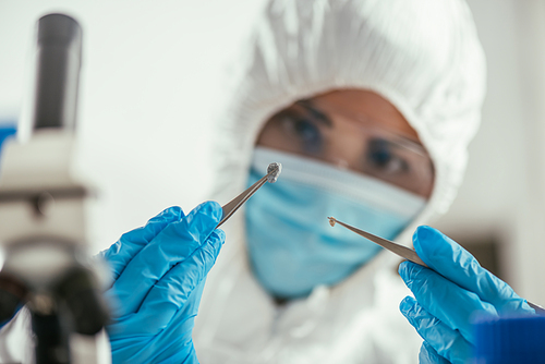 selective focus of biochemist holding small stone with tweezers