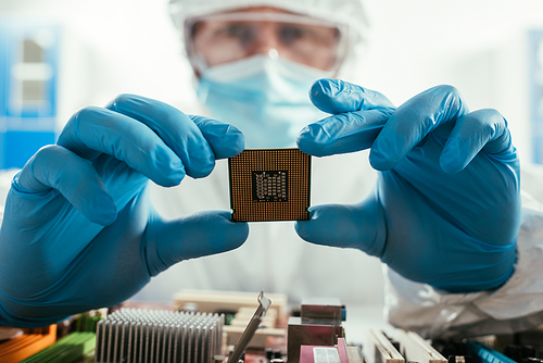 selective focus of engineer holding microchip near computer motherboard