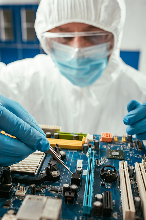 selective focus of engineer holding tweezers while testing computer motherboard