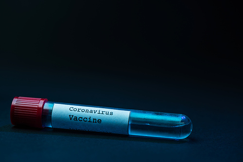 Sample tube of coronavirus vaccine on dark background