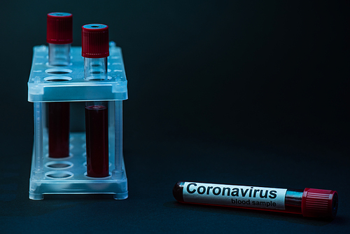 Coronavirus blood sample near test tube rack with tubes on dark