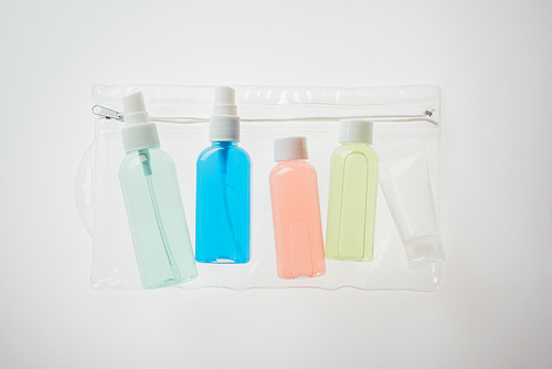 colorful bottles with liquids in cosmetic bag on white background