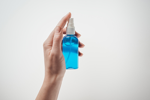 cropped view of woman holding bottle with liquid on white background