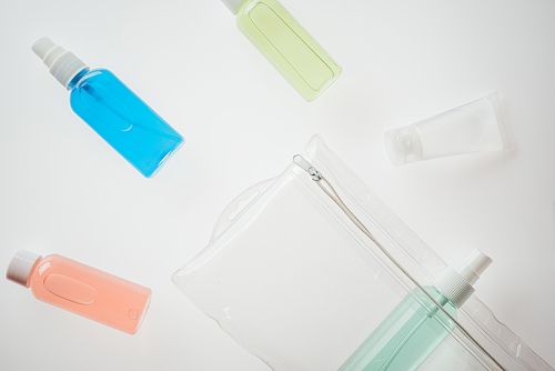 top view of cosmetic bag and bottles with liquids on white background