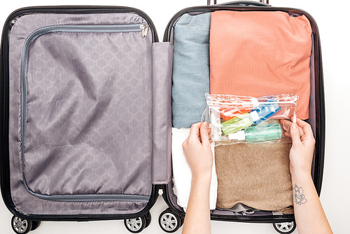 cropped view of woman packing travel bag on white background