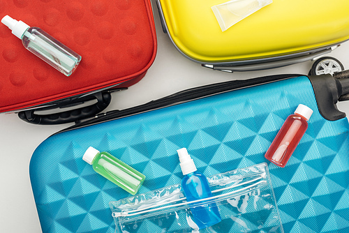 top view of bright bottles with liquids on travel bag