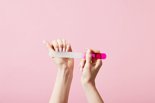 Cropped view of woman doing manicure using nail file isolated on pink
