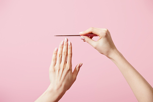 Cropped view of woman with nail file isolated on pink
