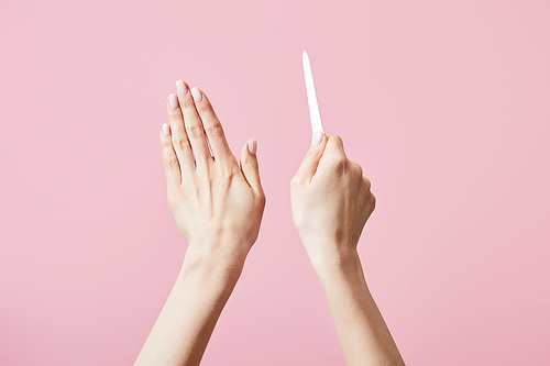 Cropped view of female hands with nail file isolated on pink