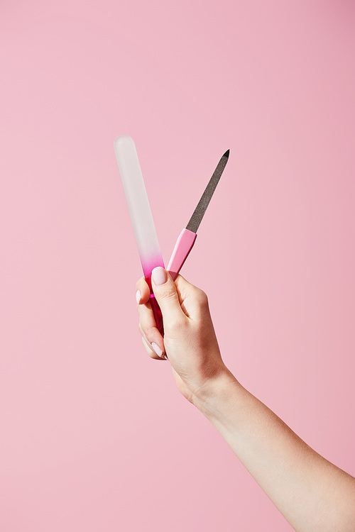 Cropped view of woman holding nail files isolated on pink