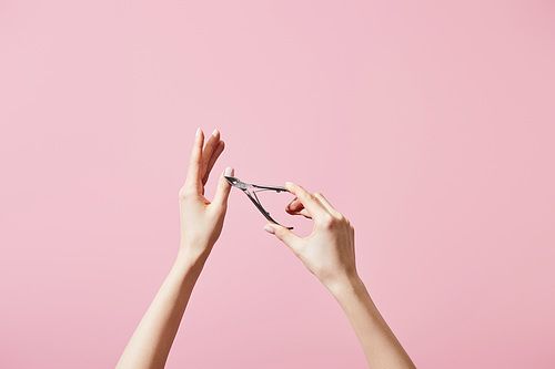 Partial view of woman cutting cuticle with nipper isolated on pink