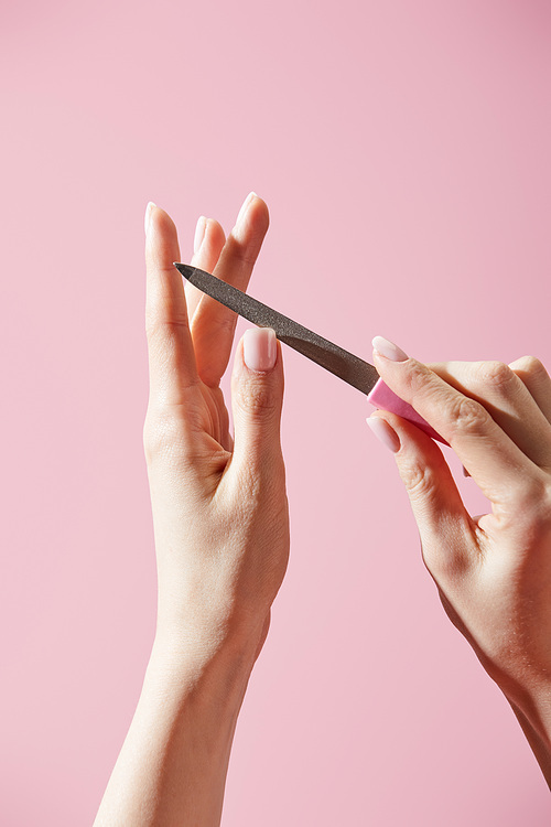 Partial view of woman filing nail isolated on pink