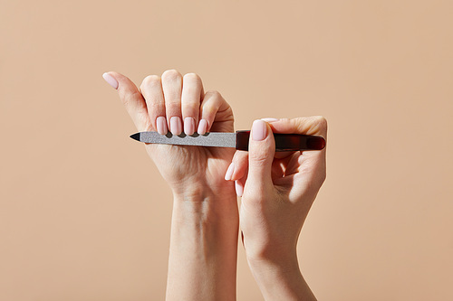 Cropped view of woman filing nails isolated on beige