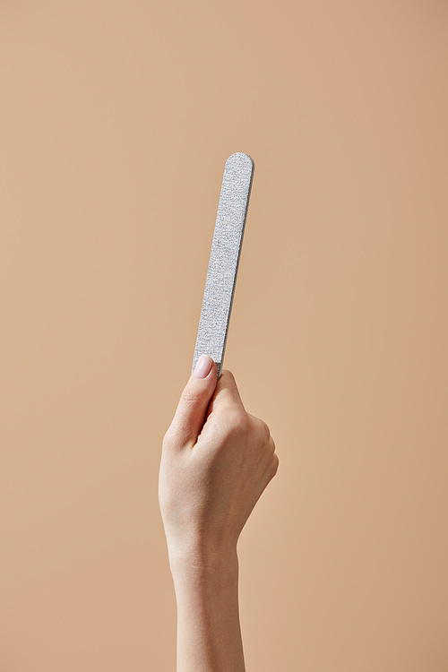 Cropped view of female hand with emery board isolated on beige