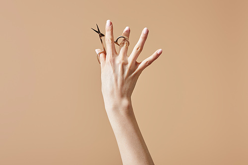 Cropped view of woman holding nail scissors isolated on beige