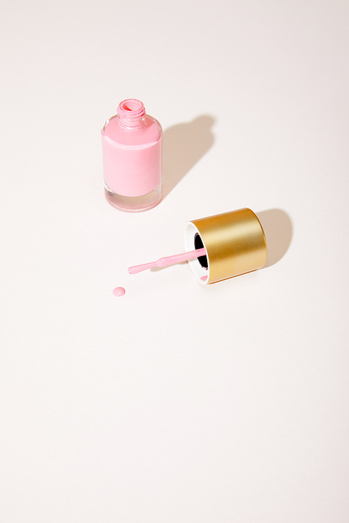High angle view of opened bottle of pink nail polish on white background