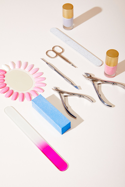 High angle view of samples of nail polish with manicure instruments on white background