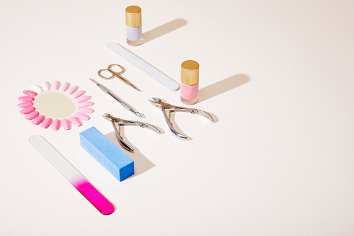High angle view of bottles and samples of nail polish with manicure instruments on white background