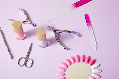 High angle view of bottles and palette of nail polish with manicure instruments on white background