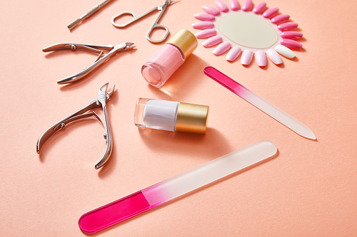 High angle view of bottles and samples of nail polish with manicure instruments on coral