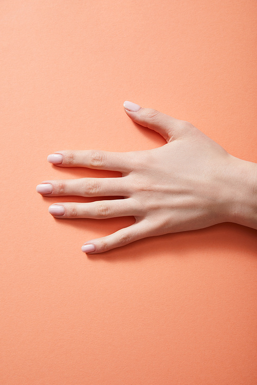 Cropped view of female hand with manicure on coral