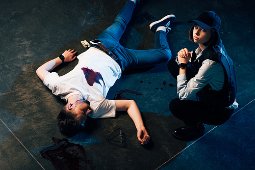 overhead view of investigator sitting near cadaver at crime scene