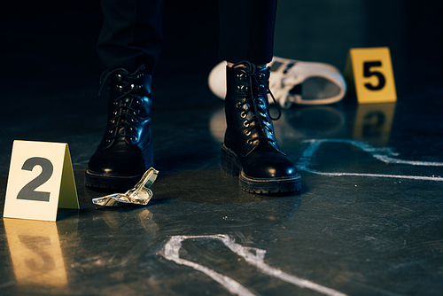 partial view of investigator standing near chalk outline and dollar banknote at crime scene