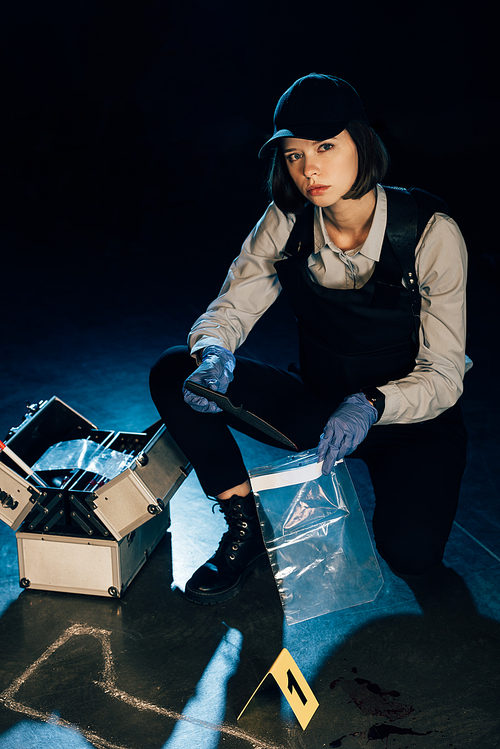 investigator holding knife and ziploc bag at crime scene