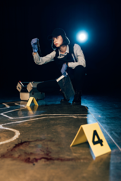 investigator holding knife and ziploc bag at crime scene