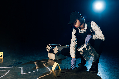 investigator holding knife and ziploc bag at crime scene