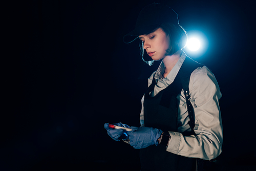 investigator in rubber gloves holding test tube at crime scene