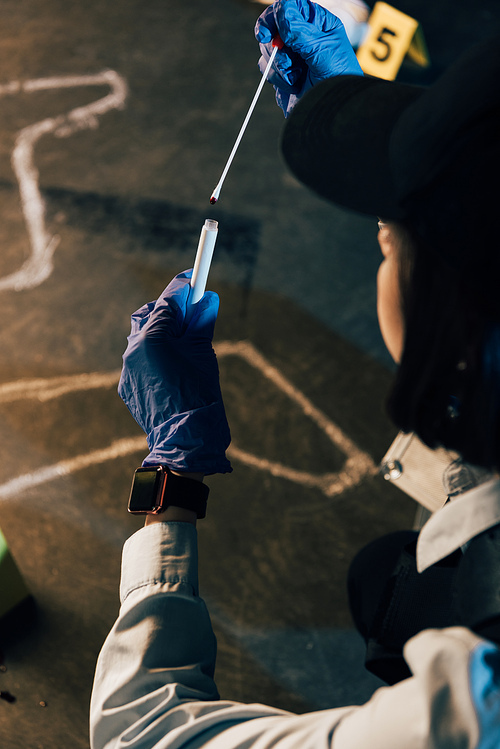 cropped view of investigator in rubber gloves holding swab and test tube at crime scene