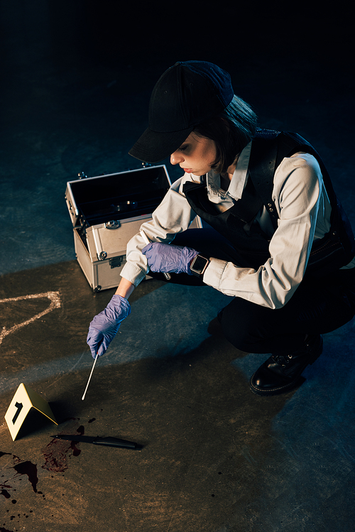 investigaror in gloves holding test tube and swab at crime scene