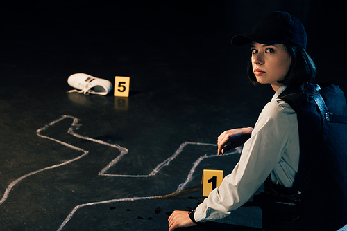 investigator sitting near chalk outline at crime scene