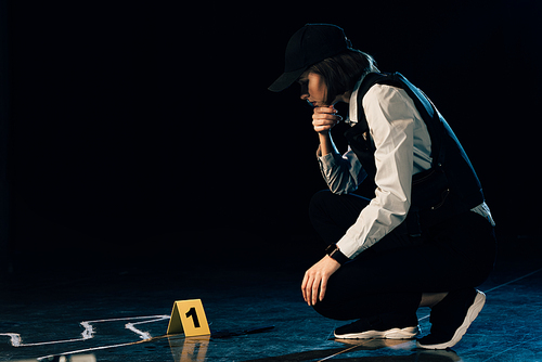 investigator sitting near chalk outline at crime scene